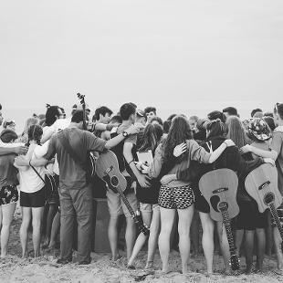 A group of students praying on the beach