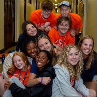 Awakening students smiling as a group in a hallway